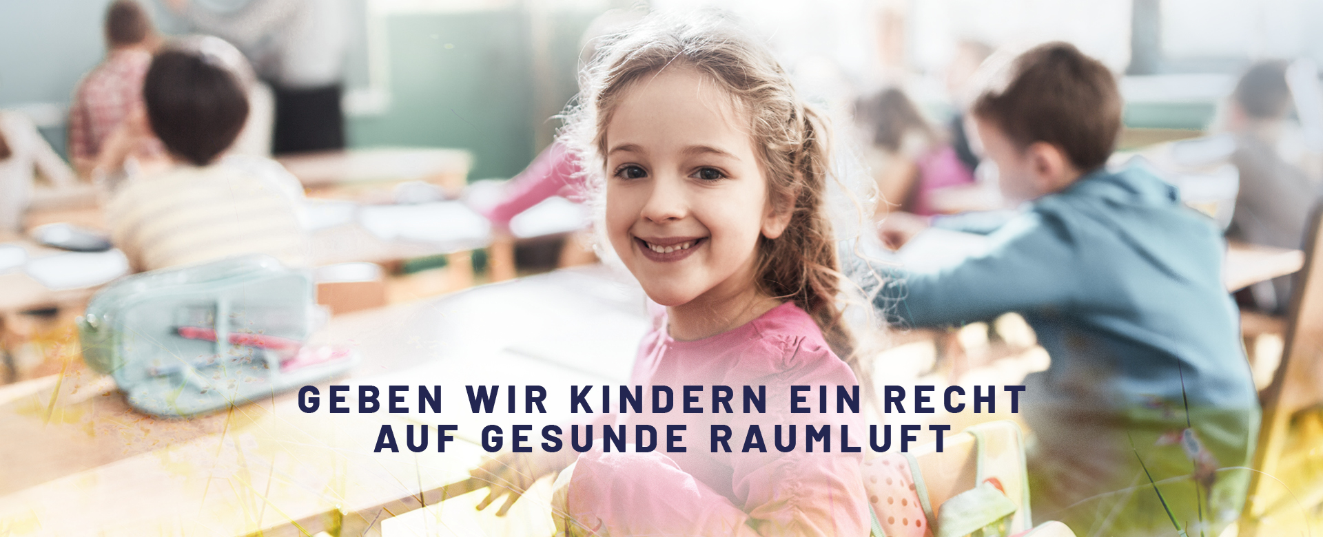 Foto einer jungen Volksschülerin in einem Klassenzimmer, welche in die Kamera lächelt
