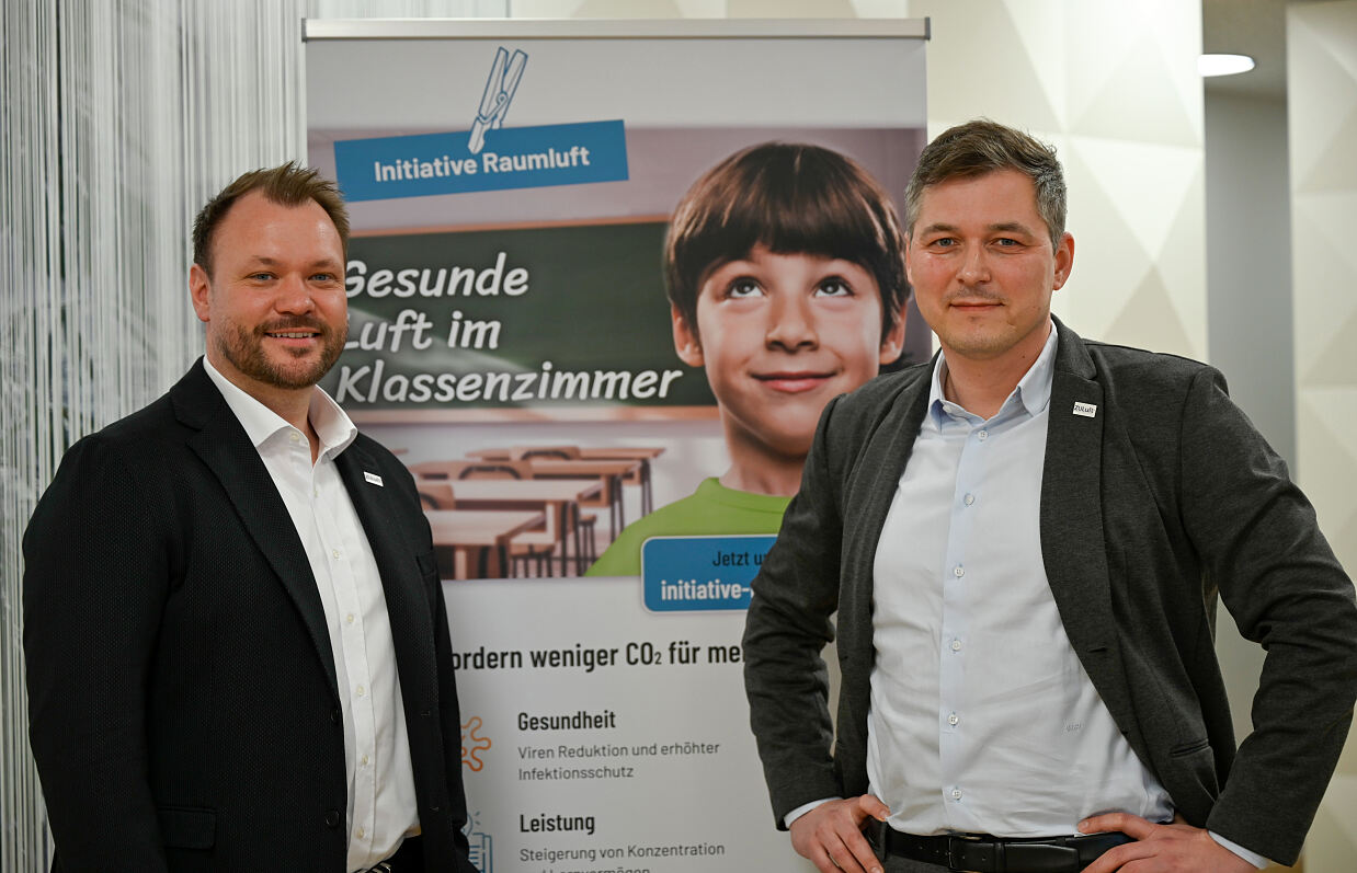 Foto von Florian Bouchal und Wolfgang Hucek vor einem Plakat mit dem Titel „Gesunde Luft im Klassenzimmer“